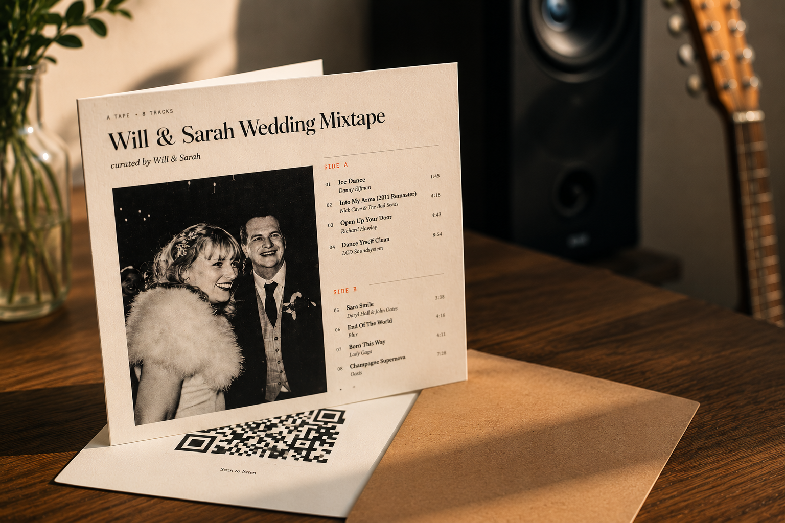 A printed mixtape greetings card standing open on a wooden desk, showing tracklist and QR code